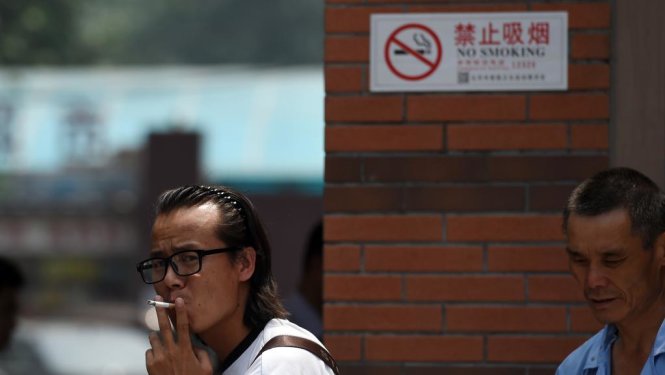 Một người Trung Quốc thản nhiên hút thuốc ngay trước biển cấm ở bệnh viện - Ảnh: AFP