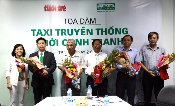 Đại diện toà soạn báo Tuổi Trẻ tặng hoa cho các khách mời tham giam buổi toạ đàm “Taxi truyền thống thời cạnh tranh” tại toà soạn báo Tuổi Trẻ sáng 2-6 - Ảnh: NGỌC DƯƠNG