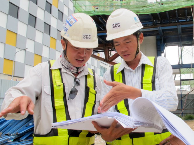 Nguyễn Văn Hiệp (phải) bàn thảo với đồng nghiệp trước khi hướng dẫn công nhân thi công - Ảnh: K.Anh