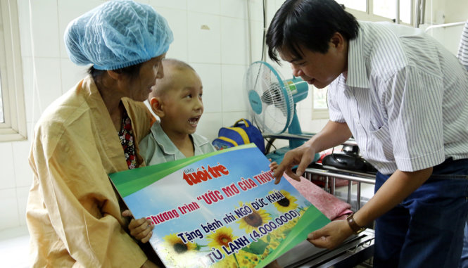 Ông Tăng Hữu Phong, tổng biên tập báo Tuổi Trẻ trao suất quà là cái tủ lạnh cho bà Nguyễn Thị Cúc, để có nước mát cho em Ngô Đức Khải - Ảnh: THÁI LỘC