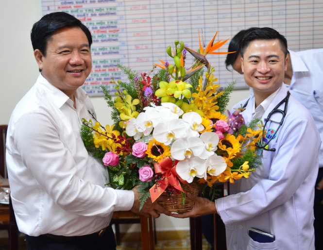 Bí thư Thành ủy TP.HCM Đinh La Thăng tặng hoa cho bác sĩ Trần Hoàng Minh - Ảnh: QUANG ĐỊNH