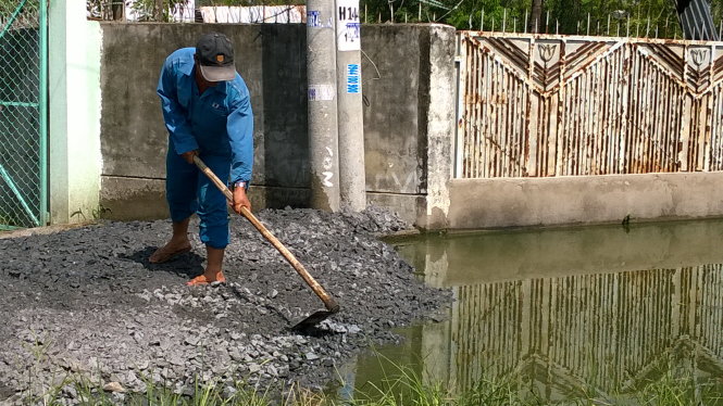 Đường ngập suốt năm, người dân phải “đắp đập” ngăn nước tràn vào nhà - Ảnh: Minh Bằng