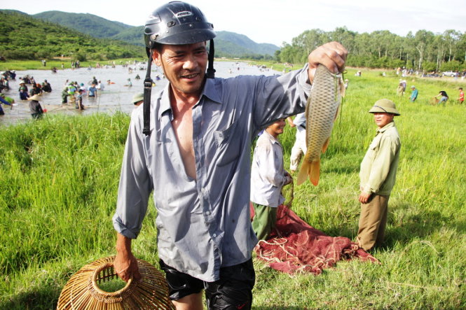 Một người dân bắt được con cá chép tại lễ hội đánh cá - Ảnh: Doãn Hòa