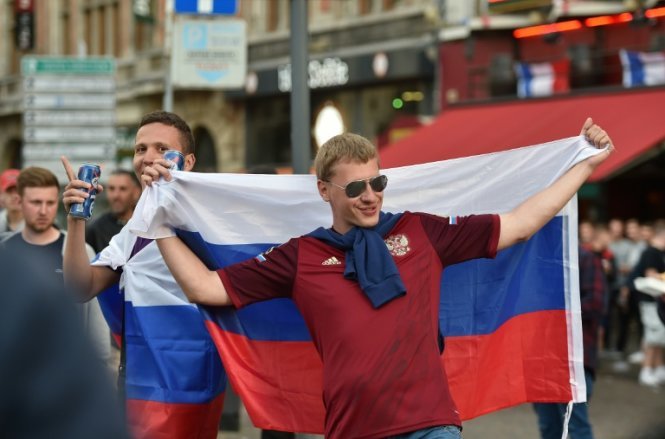 Một cổ động viên khoác cờ Nga đứng bên ngoài một quán bar ở Lille ngày 14-6 - Ảnh: AFP