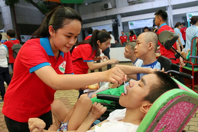 Chiến sĩ Hoa phượng đỏ chăm sóc các em tại Trung tâm Bảo trợ trẻ khuyết tật và mồ côi Thị Nghè - Ảnh: Ngọc Hiển