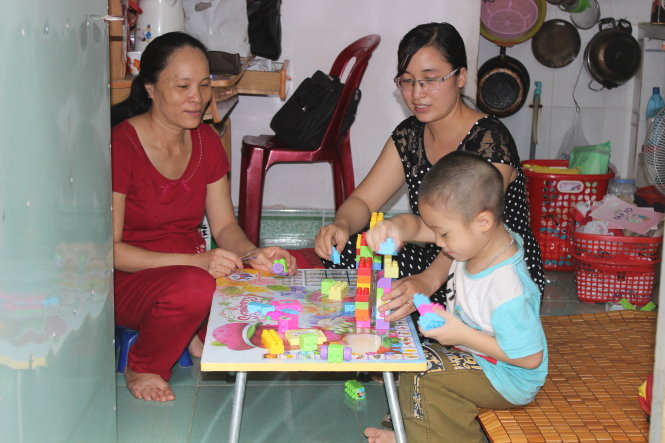Cô giáo Thêm (phải) chơi cùng bé Trần Minh Quang. Ngồi cạnh là chủ nhà tốt bụng Lê Thị Trình - Ảnh: H.NHƠN