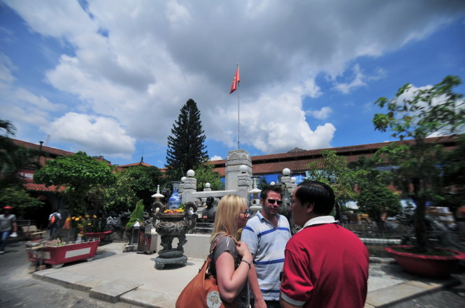 Du khách nước ngoài được hướng dẫn viên người Việt giới thiệu về kiến trúc và nét văn hóa của chợ Bình Tây, Q.6, TP.HCM - Ảnh: Hữu Thuận