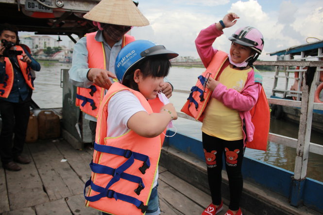 Trẻ em đi đò được hướng dẫn mặc áo phao (ảnh chụp tại bến đò Phú Cường, H.Củ Chi, TP.HCM - TP Thủ Dầu Một, Bình Dương) - Ảnh: Hồ Đức