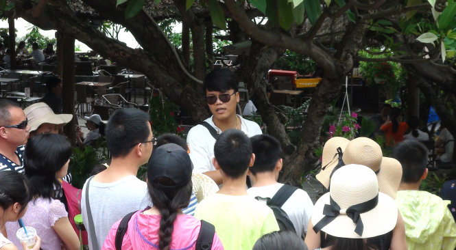 Một hướng dẫn viên người Trung Quốc hướng dẫn du khách tham quan danh thắng quốc gia Hòn Chồng (TP Nha Trang, Khánh Hòa) trưa 28-6 - Ảnh: Duy Thanh