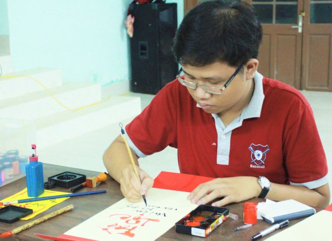 Minh Khuê chăm chú viết thư pháp trong chiến dịch “Xuân tình nguyện” - Ảnh: Tuyết Mai