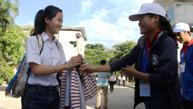 Một thí sinh được các tình nguyện viên thuộc trường Cao đẳng Du lịch Huế tặng hoa hồng tại điểm thi trường ĐH Sư phạm Huế vào chiều 1-7 - Ảnh: NHẬT LINH