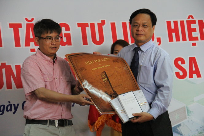 Tiến sĩ Trần Đức Anh Sơn (bên trái) trao tư liệu là những cuốn Alat cổ do Trung Quốc và các nước khác xuất bản khẳng định chủ quyền của Trung Quốc về phía nam chỉ tới đảo Hải Nam- Ảnh: TRƯỜNG TRUNG