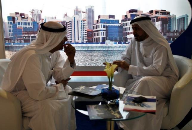 Các doanh nhân trong trang phục truyền thống đang trò chuyện với nhau tại một triển lãm bất động sản tại Dubai - Ảnh: Reuters
