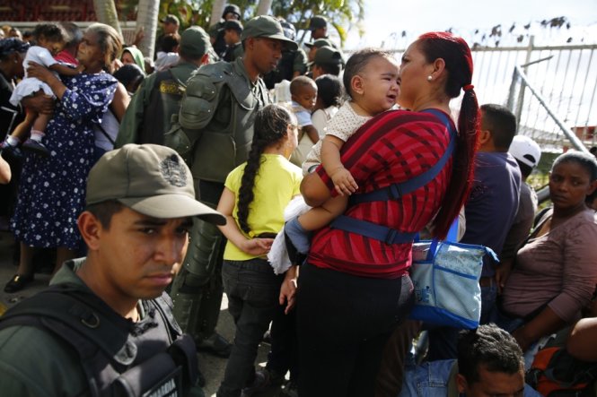 Lực lượng bảo vệ Venezuela giám sát một đám đông tại cửa hàng rau thuộc quản lý nhà nước ở Caracas - Ảnh: Reuters