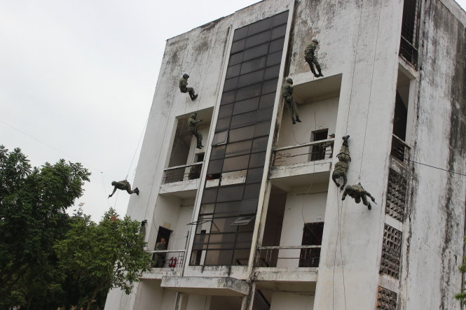 Các chiến đấu viên đội 12 thực hiện kỹ thuật đổ treo tụt dây tiếp cận mục tiêu trên tòa nhà bốn tầng cao 15m - Ảnh: M.LĂNG
