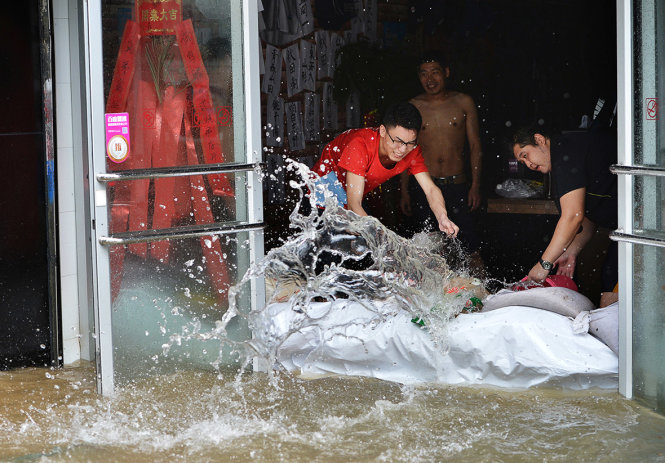 Người dân tát nước tràn vào nhà ở TP Vũ Hán, tỉnh Hồ Bắc, Trung Quốc - Ảnh: Reuters