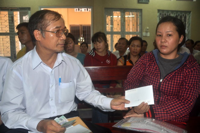 Đại diện Công ty Nghê Huỳnh (trái) trao số tiền bồi thường cho chị Đỗ Thị Ngọc Giàu (phải)- ngư dân Long Sơn tại trụ sở TAND TP Vũng Tàu chiều 15-7 - Ảnh: ĐÔNG HÀ
