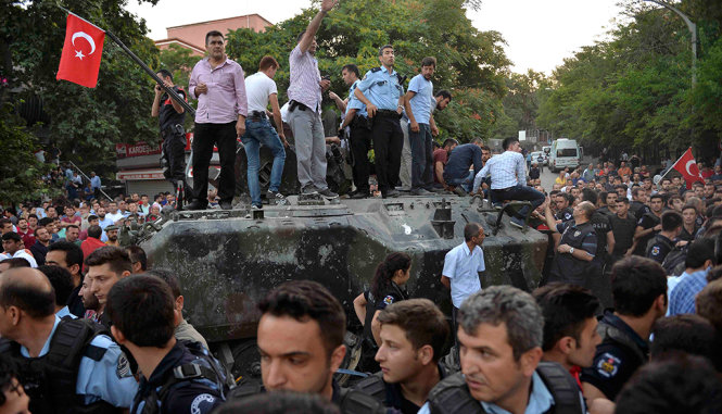 Cảnh sát Thổ vây quanh một xe tăng của lực lượng quân đội đảo chính. Cho tới 11g sáng 16-7, nhiều binh lính thuộc phe đảo chính đã bị bắt hoặc đầu hàng - Ảnh: REUTERS