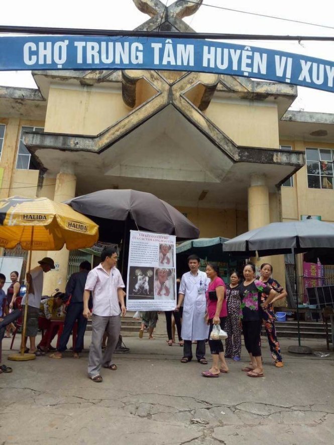 Bác sĩ Chung với tấm biển xin tiền giữa chợ Vị Xuyên - Ảnh: NGUYỄN THỊ MAI