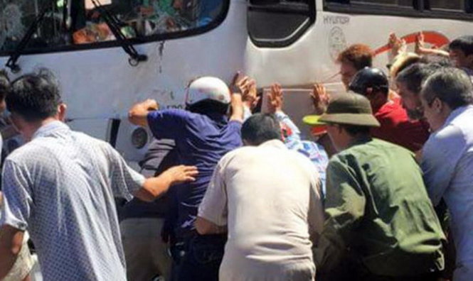 Người dân cùng nhau đẩy lùi xe khách để đưa nạn nhân bị kẹt ra ngoài - Ảnh: CTV