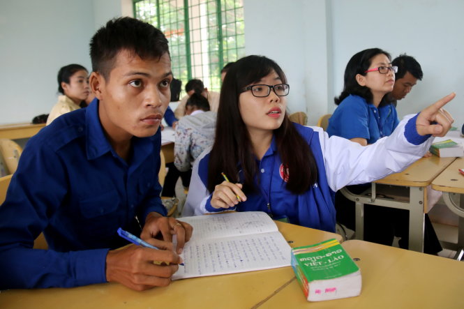Sinh viên Đoàn Hồng Vân (Trường ĐH Ngoại thương TP.HCM) hướng dẫn cách viết tiếng Việt cho học viên Lào trong lớp học “1 kèm 1” - Ảnh: N.Hiển
