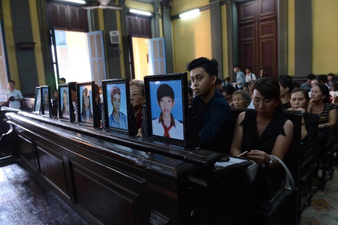 Gia đình nạn nhân mang theo di ảnh của những người đã bị sát hại trong vụ án đến tòa - Ảnh: Duyên Phan