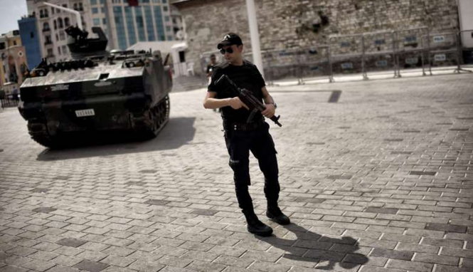 Một cảnh sát đứng cạnh một chiếc xe bọc thép được dùng trong cuộc đảo chính - Ảnh: AFP