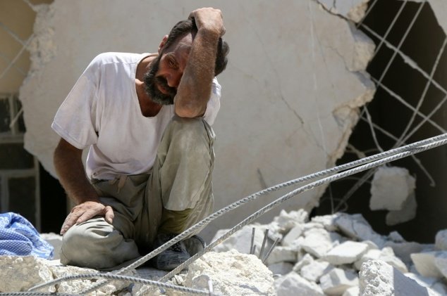 Một người đàn ông Syria đau khổ trước đống đổ nát của tòa nhà sau vụ không kích tại Aleppo, miền bắc Syria ngày 17-7 - Ảnh: AFP