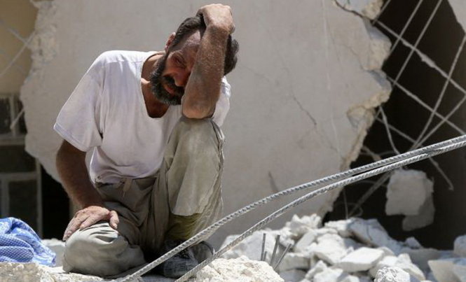 Một người đàn ông suy sụp giữa đống đổ nát của một tòa nhà bị không kích ở Syria - Ảnh: AFP