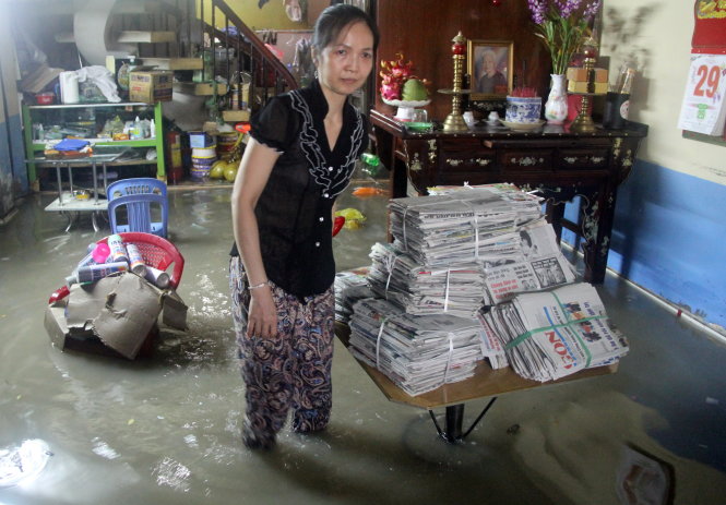 Chị Lê Hoàng Trang Châu thu dọn đồ đạc trong căn nhà ngập nước sau cơn mưa ngày 23-7 - Ảnh: Q.KHẢI