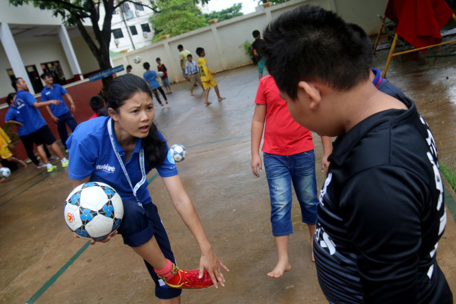 Cứ đúng 7g30 mỗi buổi sáng, các em học sinh Trường tiểu học Seng A Lun (tỉnh Champasak) lại tập trung trước sân trường để học kỹ thuật đá bóng. Sinh viên Đỗ Thị Ngọc Linh (Trường ĐH Sư phạm TDTT TP.HCM) cho biết dù các em không biết tiếng Việt, các sinh viên cũng không biết tiếng Lào nhưng cả hai đều có một điểm chung là rất yêu bóng đá - Ảnh: NGỌC HIỂN