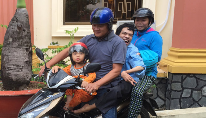 Sau khi nhận quyết định hoãn xử, Tùng được vợ chồng anh kế Phạm Văn Sơn bế lên xe máy để về nhà - Ảnh: N.TRIỀU