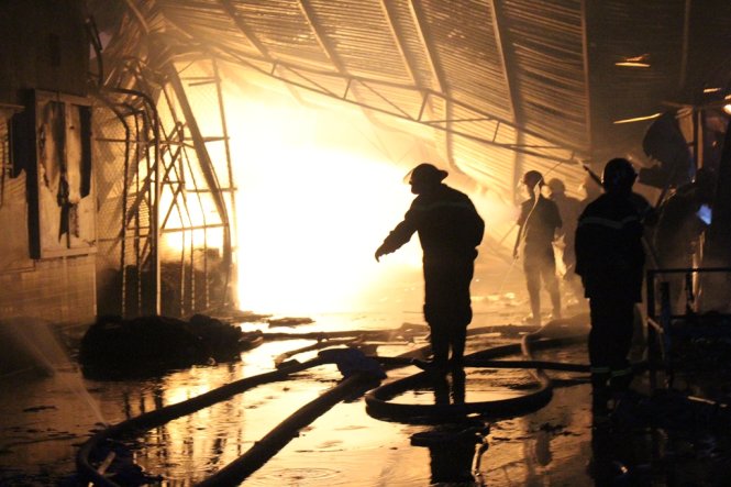 Đến 19g30 lực lượng chữa cháy vẫn đang nỗ lực phun nước dập lửa phía trong kho phế liệu Việt Xanh - Ảnh: ĐÌNH TRỌNG