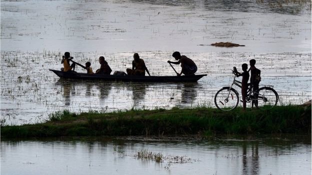 Dân làng ở bang Assam, Ấn Độ dùng xuồng đi lại trong vùng lũ - Ảnh: EPA