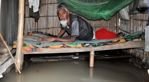 Một cụ ông người Bangladesh chật vật trong căn nhà bị ngập do lũ - Ảnh: BBC