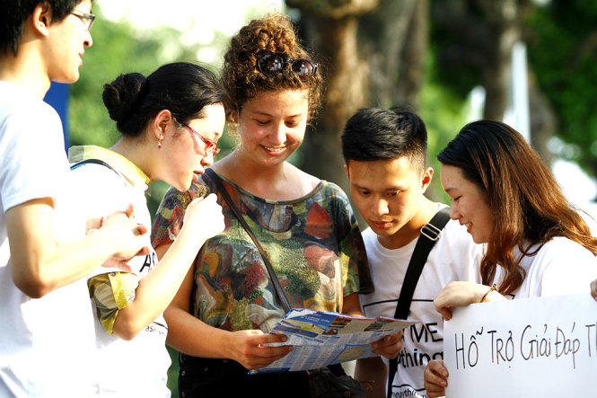 Các thành viên trong nhóm Ask Me Anything trò chuyện với du khách nước ngoài tại bờ hồ Hoàn Kiếm chiều 30-7 - Ảnh: NAM TRẦN