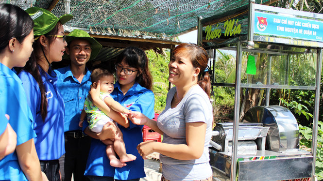 Các bạn trẻ quận 10 tặng xe nước mía cho gia đình chị Mai Trinh (bìa phải) tại xã Hiệp Phước (Nhà Bè) để thêm cơ hội ổn định cuộc sống - Ảnh: Q.L.