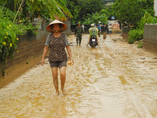 Bà Bùi Thị Phương, tổ trưởng tổ 29 khu 3 vừa nhận tiếp tế hai chiếc bánh mì từ người nhà. Nhà và bếp của gia đình bà Phương đã bị ngập sau trận mưa lớn rạng sáng 3-8 - Ảnh: Đức Hiếu