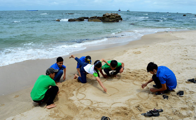 Hết mình thể hiện tác phẩm hội hoạ trên cát - Ảnh: HOÀNG TRUNG
