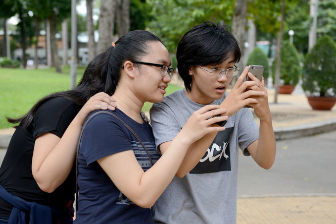 Một nhóm bạn trẻ hồi hộp khi bắt Pokemon tại công viên Tao Đàn chiều 8-8 - Ảnh: DUYÊN PHAN