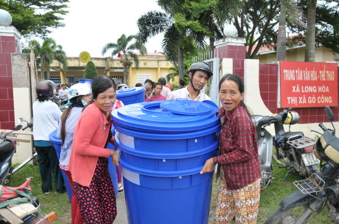Người dân vui mừng mang thùng chứa nước về nhà - Ảnh: THANH TÚ