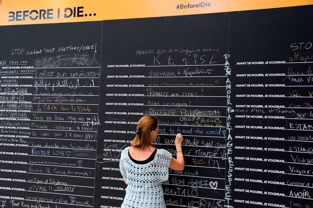 Một hành khách nữ điền nốt vào phần bỏ trống của câu “Trước khi tôi chết...” - Ảnh: AFP