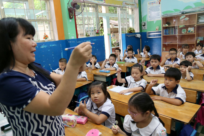 Cô Trần Yến Linh đang hướng dẫn học sinh lớp 1/3 trường tiểu học Trần Bình Trọng Q5, TP.HCM cách cầm viết trong ngày tựu trường - Ảnh: NHƯ HÙNG