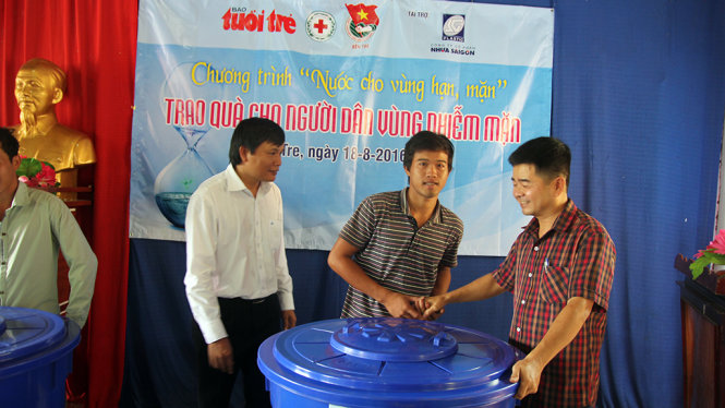 Người dân vùng nhiễm mặn xã Long Định, huyện Bìn Đại, tỉnh Bến Tre nhận thùng chứa nước để trữ nước mưa từ đại diện báo Tuổi Trẻ và nhà tài trợ - Ảnh: Mậu Trường