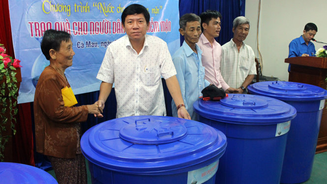 Đại diện báo Tuổi Trẻ trao thùng chứa nước của chương trình “Nước cho vùng hạn - mặn” cho người dân xã Khánh Hưng (Cà Mau)