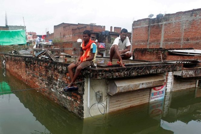 Người dân ở TP Allahabad, bang Uttar Pradesh, Ấn Độ trèo lên mái nhà tránh lũ - Ảnh: REUTERS