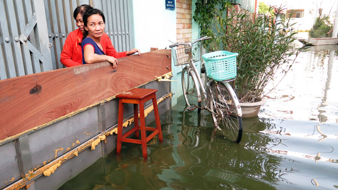 Người dân che chắn phía trước cửa cổng nhưng nước vẫn tràn vào nhà