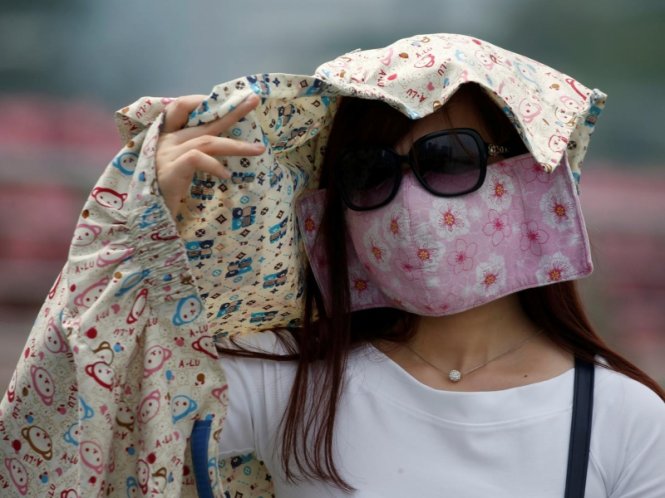 Một phụ nữ phải che kín mặt mũi để tránh nắng và khói bụi - Ảnh: Reuters