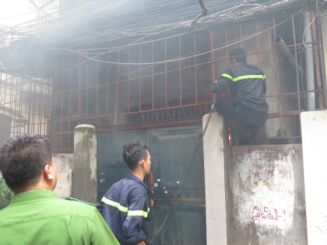 Cảnh sát PCCC phá cửa nhà để dập lửa - Ảnh: QUANG THẾ