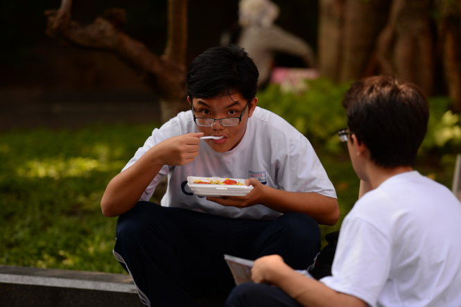 Một học sinh ăn vội trước một điểm học thêm tại quận 3, TP.HCM - Ảnh: Hữu Khoa